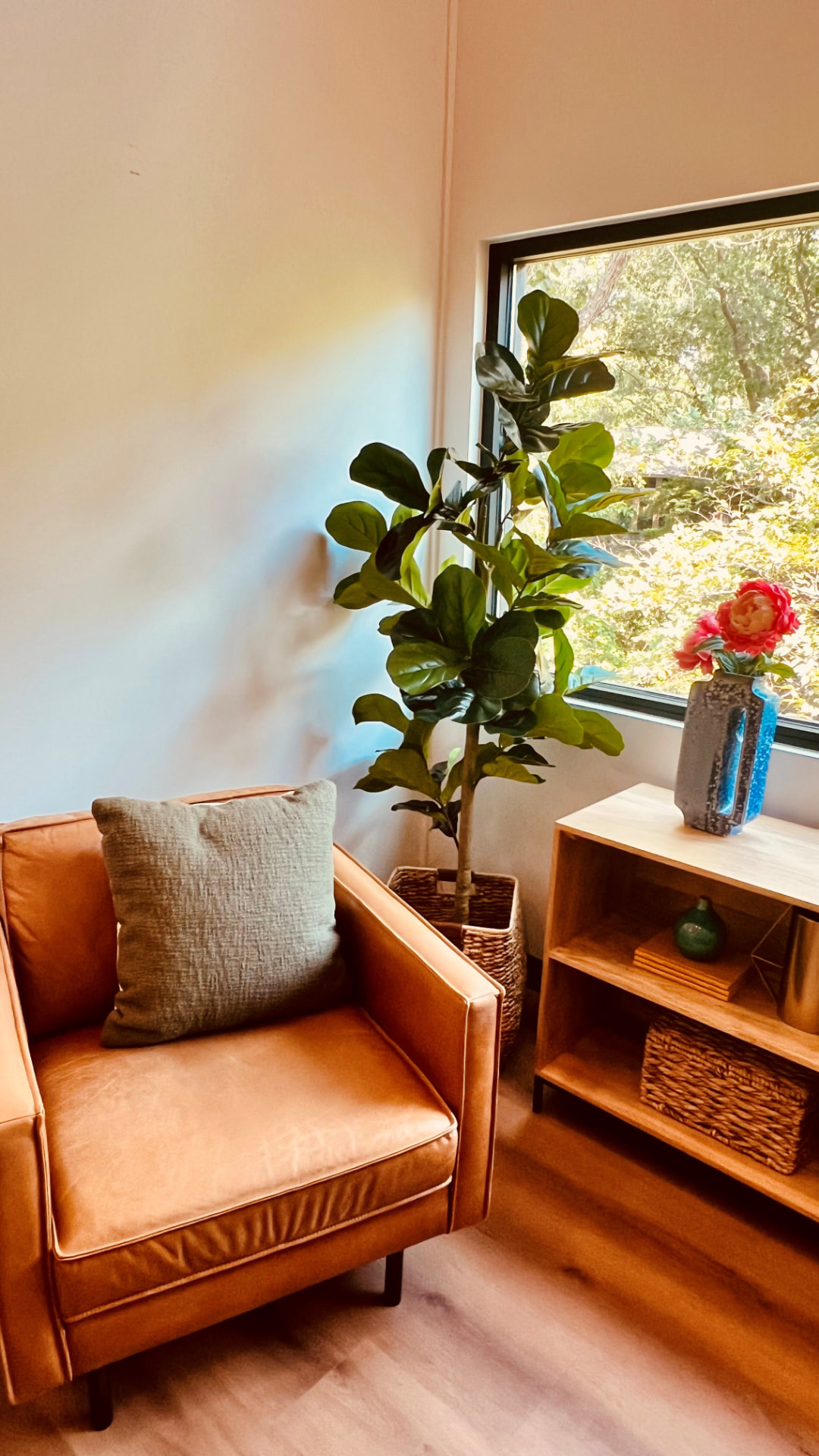 A sunlit corner of a Dallas Therapy Associates office with a leather chair, plants, and a garden view
