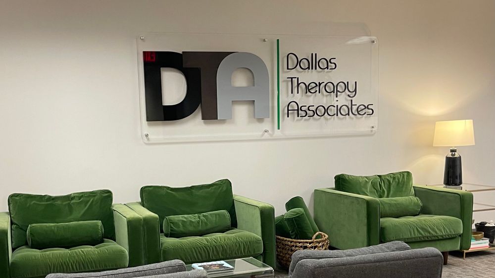 The Dallas Therapy Associates waiting room with green velvet chairs and the DTA logo