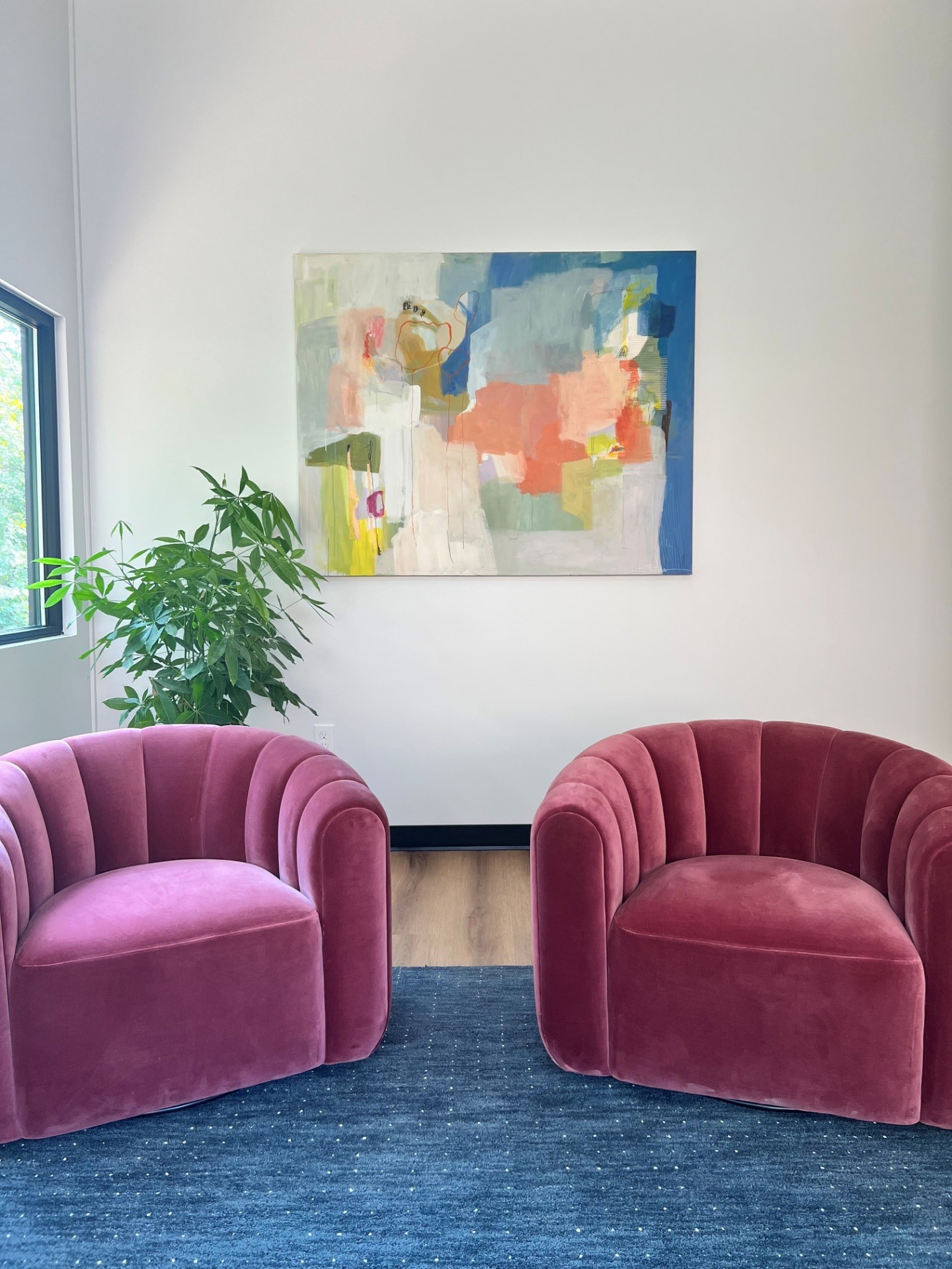 Two blush velvet chairs beneath a colorful abstract painting in a Dallas Therapy Associates office